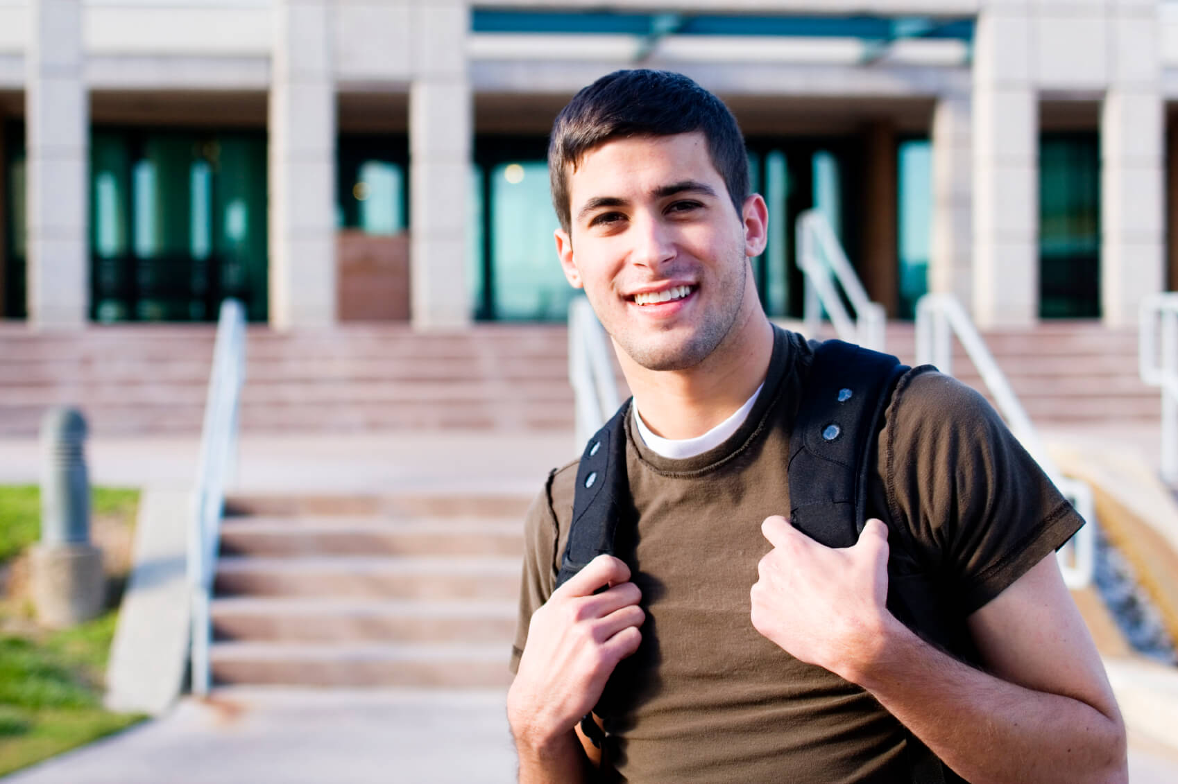 student standing with backpack in front of building