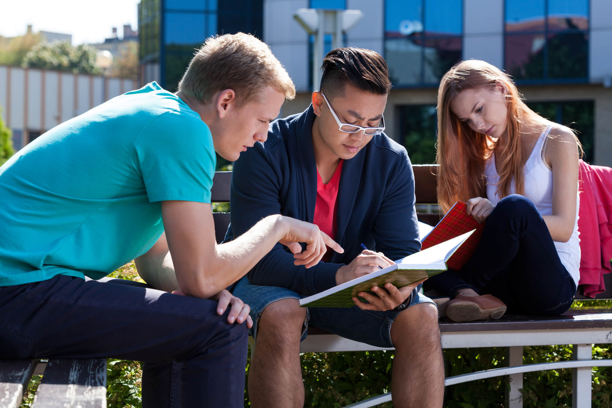 students outside studying on bench