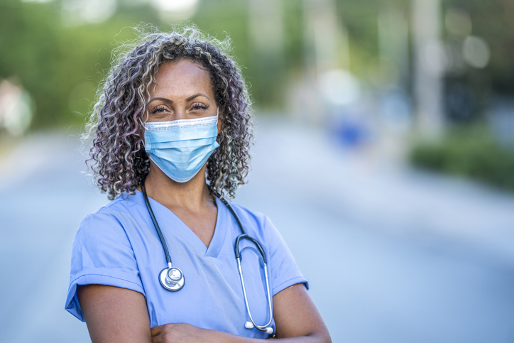 Nurse standing proudly with mask on.